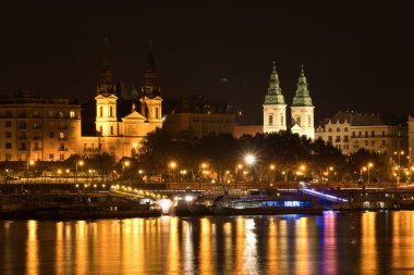 Budapeşte, Macaristan - 25 Ekim 2021: Macaristan 'daki Szechenyi Zinciri Köprüsü' nde karanlık bir yaz gecesinde Tuna Nehri 'nin yanındaki Kutsal Bakire Meryem Kilisesi.