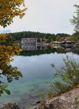 Bavyera, Almanya - 6 Ekim 2019: Almanya 'da bulutlu bir sonbahar gününde Eibsee boyunca suda inşa ve yansıma.