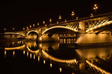 Budapeşte, Macaristan - 25 Ekim 2021: Macaristan 'ın Budapeşte kentinde bir yaz gecesinde Tuna Nehri' nde Margaret Köprüsü ve yansıması aydınlandı. 