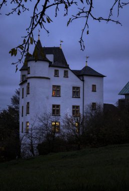 Nennig, Almanya - 19 Kasım 2021: Almanya 'da bulutlu bir sonbahar akşamında Victor' s Residenz Hotel Schloss Berg 'in camlarında ışıklar.