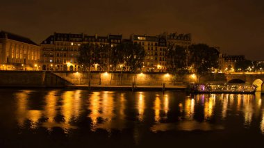 Paris, Fransa - 23 Haziran 2021: Paris 'te bir yaz gecesinde arka planda binalar bulunan Seine Nehri üzerindeki ışıkların yansıması. 