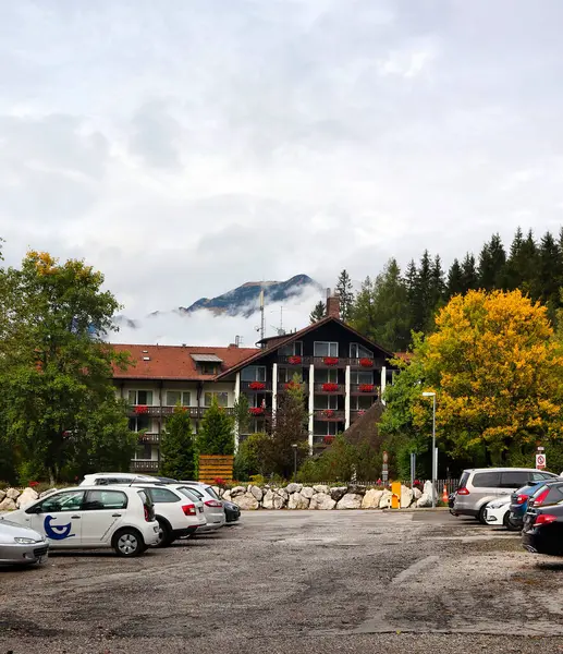 Bavyera, Almanya - 6 Ekim 2019: Bavyera 'da bulutlu bir sonbahar gününde Eibsee' de çiçek kutularında kırmızı çiçeklerle dağları kaplayan sis. 