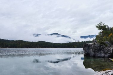 Almanya 'nın Bavyera şehrinde bir sonbahar gününde Eibsee' nin arkasındaki bir dağın üzerinde bulutlar var.. 