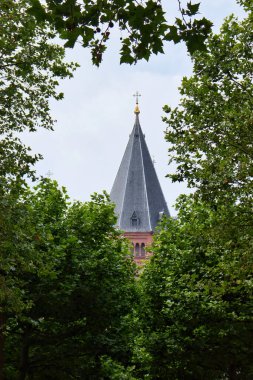 Mainz, Almanya - 25 Haziran 2021: Mainz Katedral Kulesi Mainz, Almanya 'da bulutlu bir yaz gününde yeşil ağaç yaprakları arasında.