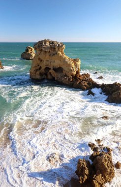 Güneşli bir kış gününde Güney Portekiz 'de Atlantik Okyanusu' ndaki büyük kayaların etrafındaki köpükler.. 