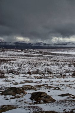 Alaska 'da karlı bir bahar gününde Dalton Karayolu boyunca dağların üzerinden sis ve kara bulutlar.. 