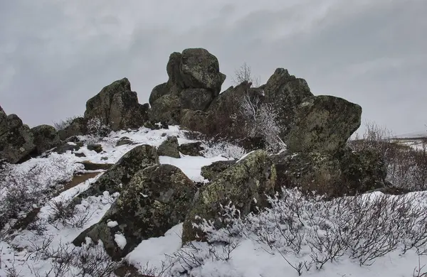 Finger Dağı 'ndaki kaya yığını bulutlu, karlı bir bahar gününde Alaska' daki Dalton Otoyolu 'nda yol kenarında..