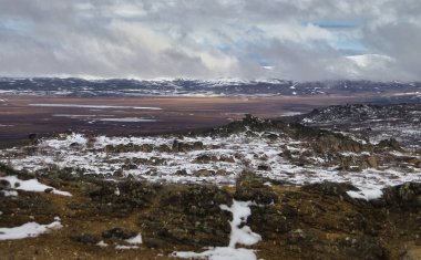 Alaska 'da bir bahar günü Dalton Otobanı' nın arka planında dağlar olan kayalar ve göl..