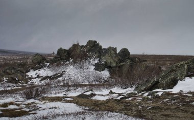Alaska 'da bir bahar günü Dalton Otobanı' nın arka planında parmak dağı olan bir tepede kayalar..