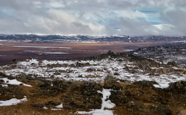 Alaska 'da bir bahar günü Dalton Otobanı' nın arka planında dağlar olan kayalar ve göl..