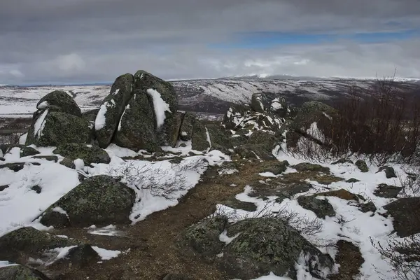Alaska 'da bir bahar günü Dalton Otobanı' nda yol kenarında kayalar ve kar.