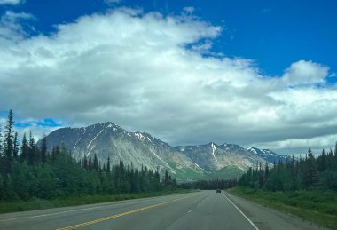 Anchorage, Alaska yakınlarındaki yolun arkasında bulutlu bir bahar gününde ışık parlıyor..