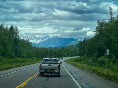 Anchorage, Alaska - 25 Haziran 2024 Anchorage, Alaska yakınlarında bulutlu bir bahar gününde dağın arkasındaki yol üzerindeki bulutlar.