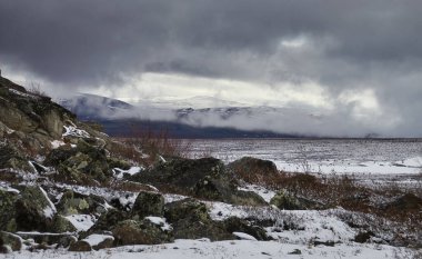 Alaska 'daki Dalton Otoyolu' nda bulutlu bir bahar gününde karlı dağı çevreleyen sis.. 
