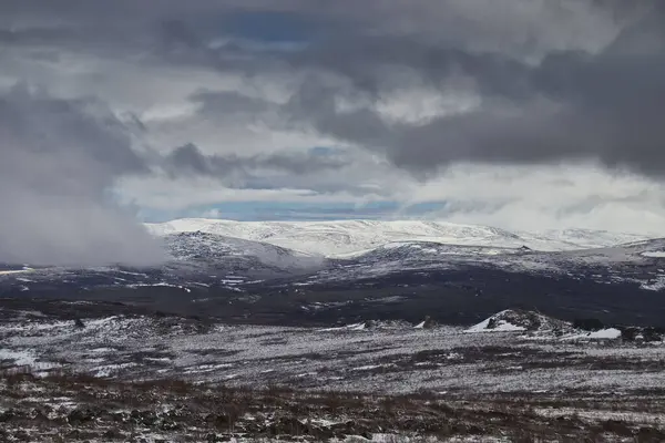 Alaska 'daki Dalton Otoyolu' nda bir bahar günü, etrafım kara bulutlarla çevrili, karlı dağlarda parlayan güneş.. 