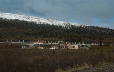 Alaska 'da güneşli bir bahar gününde Dalton Otobanı' ndaki boru hattının yanındaki eski binalar.. 