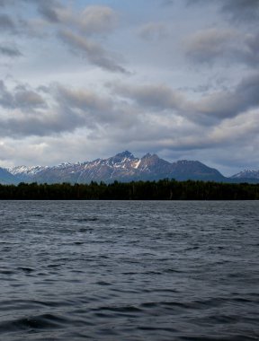 Alaska, Wasilla 'da bir yaz gecesinde Lucille Gölü' nün arkasındaki dağlarda bulutlar var.. 