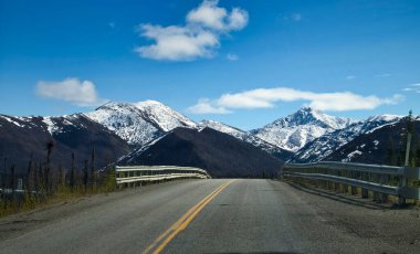 Alaska 'da güneşli bir bahar gününde Dalton Otoyolu' nun asfalt kaplı kısmında köprü. 