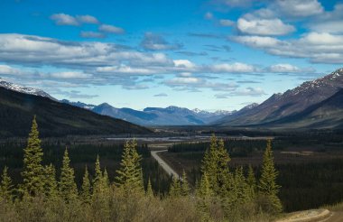 Alaska 'da güneşli bir bahar gününde Dalton Highway dağların arasından geçiyor.. 
