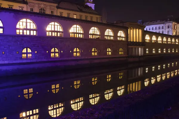 Ljubljana, Slovenya - 15 Ocak 2022: Ljubljana 'da bir kış gecesinde Ljubljanica Nehri' ndeki Renkli Merkez Pazar ve Yansıma. 