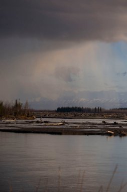 Bir bahar akşamı Salcha, Alaska 'da Salcha Nehri' nin arkasında bulutlar ve yağmur var..
