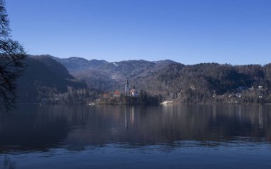 Bled, Slovenya - 16 Ocak 2022: Slovenya 'nın Julian Alplerinde güneşli bir kış günü Bled Adası' ndaki Bled Adası 'ndaki Meryem Ana Kilisesi. 