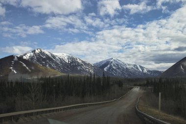 Alaska 'da güneşli bir bahar gününde Dalton Otoyolu etrafındaki dağlar. 