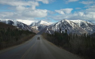 Alaska 'da güneşli bir bahar günü, Dalton Otoyolu' nun asfalt kaplı bölümünde giden bir kamyon.. 