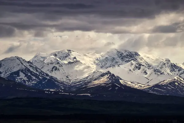 Güneş bulutların arasından parlıyor. Karlı dağda. Delta Kavşağı, Alaska yakınlarında.. 