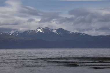 Güneş bulutların arasından parlıyor dağların üzerinden Homer, Alaska 'daki Bishop Sahili' nde bir yaz günü.