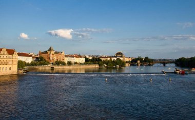 Prag, Çek Cumhuriyeti - 3 Temmuz 2021: Prag 'da güneşli bir yaz akşamında Vltava Nehri' nin yanındaki binalar.