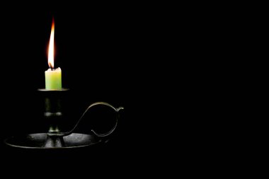 Eski bir pirinç odacık mum tutacağında yanan mum kopyalama alanı ile siyah arkaplanda izole edilmiş.