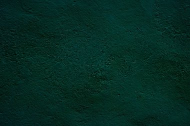 Koyu yeşil veya yeşil yüzeyi olan bir duvar resmi tasarım projeleri veya sunumlar için ideal, doğal ve gizemli bir atmosferi çağrıştıran minimalist ve modern bir arkaplan..