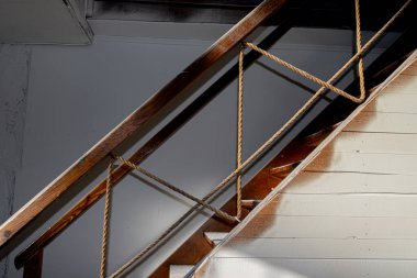 Sanatsal güneş ışığıyla aydınlatılan korkuluklar gibi doğal halatın yer aldığı ahşap bir merdiven manzarası..