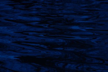 Derin mavi tonlarda dalgalanan suyun soyut dokusu, dingin hareket ve karmaşık yansımaları yakalamak, arka plan, rahatlama temaları veya su konseptleri için ideal.