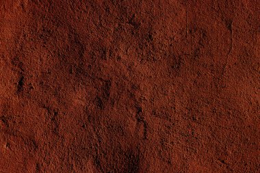 Toprağı ya da toprak dokusunu andıran parlak kırmızı ve kahverengi desenli yüzey. Doğal temalar ya da arka planlar için ideal.