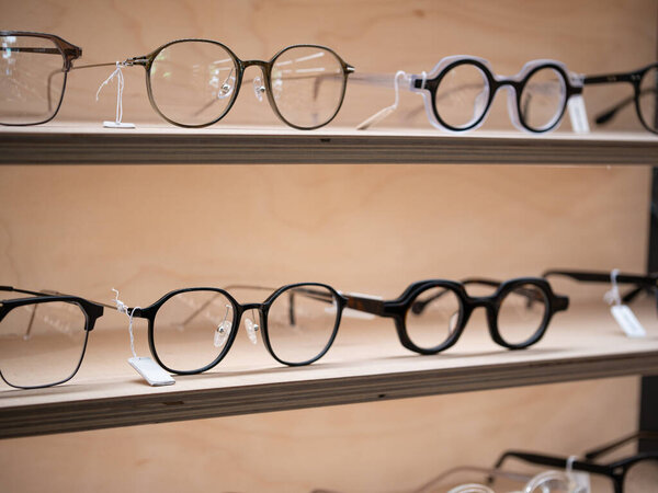 close-up wooden shelves full of modern trendy eyeglasses in optical shop