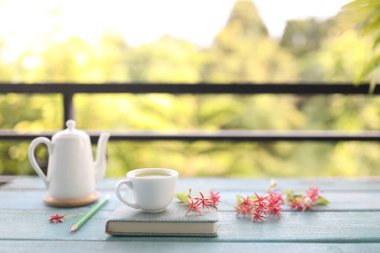 Beyaz çay fincanı, klasik çay demliği ve tahta masada pembe Rangoon sürüngen çiçekleri.