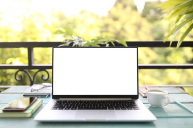 Laptop ön manzara ve beyaz cam masaya dizilmiş beyaz kahve fincanı.