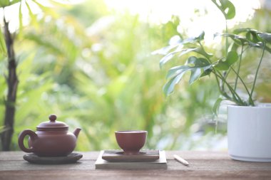 Brown teapot and tea cup and books on wooden table
