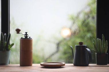 coffee glass cup and blue drip pot on wooden table in front of window