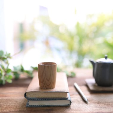 Wooden tea cup and vintage black tea pot on wooden table