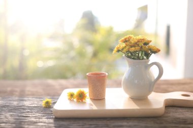 Yellow Chrysanthemum flower and pink tea cup on wooden tea