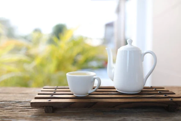 White tea pot and tea cup on tray wooden table