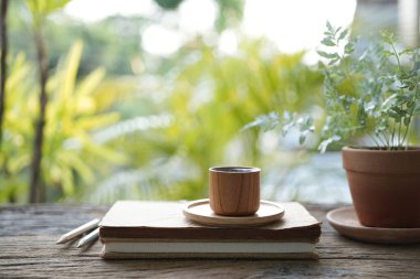 defter ve bambu ahşap kahve fincanı ahşap masada yeşil manzaralı.