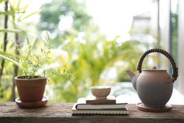 Küçük çay fincanı ve eski demlik ahşap masada, defterli.