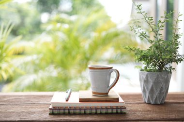 Klasik seramik kahve fincanı ve defterler ve kahverengi ahşap masaya demlik.