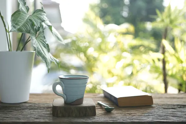 Coffee mug and old book and plant pot on weathered wooden table