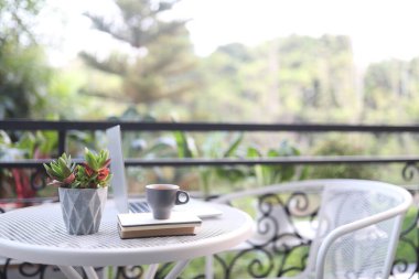 Laptop manzarası ve beyaz masa üzerinde not defterleri olan kahve fincanı.