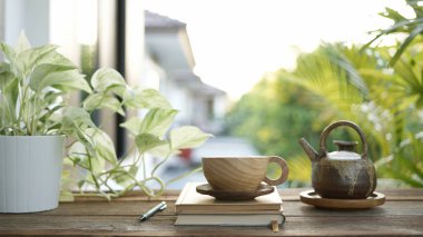 Çay fincanı ve eski toprak kap çaydanlığı balkonda.